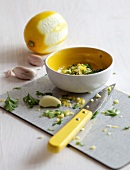 Chopped garlic and parsley in bowl with lemon for preparation of gremolata