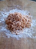 Orange noodles on wooden board