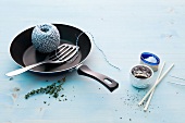 Frying pan, string, spatula and chopsticks on blue background