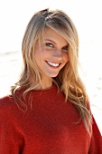 Portrait of pretty blonde woman with long hair wearing red sweater, smiling
