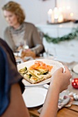 Woman holding plate with vegetable quiche and smoked salmon