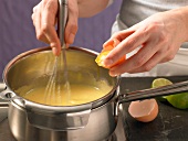 Close-up of hand adding egg yolk in casserole for preparation of Hollandaise