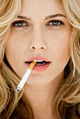 Portrait of beautiful blonde woman holding cigarette, close-up