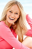 Portrait of happy blonde woman wearing pink sweater, smiling widely