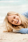 Close-up of happy blonde woman enjoying on the sand, laughing