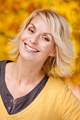 Portrait of happy blonde woman wearing yellow sweater smiling with head slightly tilted