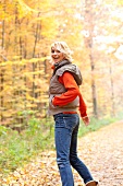 Happy blonde woman wearing gray puffer jacket looking over shoulder, laughing