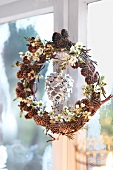 Close-up of Christmas wreath with pinecones and flowers, hanging