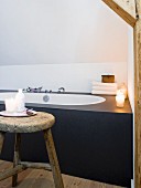 Fitted designer bathtub and rustic wooden stool