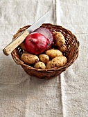 Winterküche, Kartoffeln und rote Zwiebeln in einem Korb, Messer