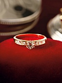 Close-up of gold ring with diamonds on red surface