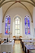 Dining room of Hopper Hotel St. Josef with colourful church window in background