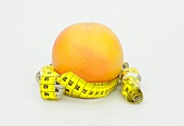 Grapefruit with measuring tape symbolizing dieting