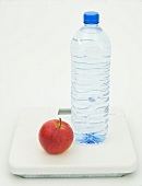 Apple and bottle of water on scales, Icon image for diet