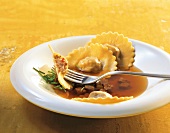 Close-up of oxtail soup with potato-bacon ravioli on plate