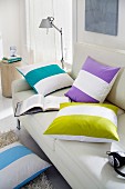 Scatter cushions with wide, brightly-coloured stripes on sofa