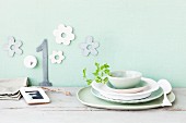 Pastel and white crockery against a wall decorated with flowers and a number 1