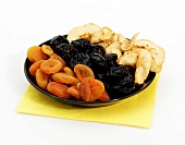 Plate of various dried fruits on white background