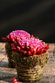 Hagebutten und Pompondahlien in Vasen aus Naturmaterialien