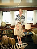 Happy blonde woman with short hair in short blouse, striped jacket and skirt, laughing