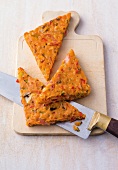 Triangular shaped gluten free pizzas with knife on chopping board