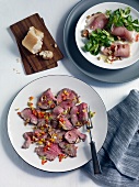 Roasted beef and corn salad with ham rolls on plate, overhead view