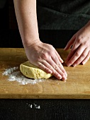 Close-up of hand Kneading dough on wooden board, step 1