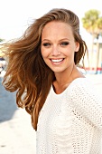 Portrait of beautiful gray eyed blonde woman wearing white knitted sweater, smiling