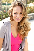 Portrait of beautiful blonde woman wearing pink and gray top, smiling