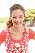 Portrait of pretty woman wearing orange-shirt and white fishnet top, smiling, close-up