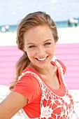 Portrait of pretty woman wearing orange-shirt and white fishnet top, smiling, close-up