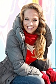 Portrait of happy blonde woman wearing winter jacket and gloves, laughing