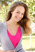 Portrait of beautiful blonde woman wearing pink and gray top, smiling