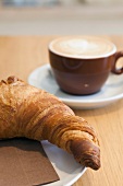 Close-up of croissant on plate with cup of coffee