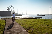 Man standing with bicycle near NDSM shipyard in IJ River, Noord, Amsterdam, Netherlands