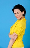 Portrait of pretty woman with short dark hair wearing yellow wrap blouse, smiling