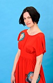 Portrait of beautiful woman with short dark hair wearing red long dress, smiling