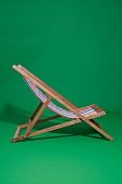 Folding deck chair with stripes pattern on green background 