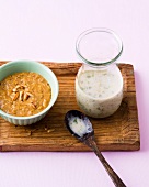 Bowl of pine nut dip and jar of coconut-coriander dip on wooden board
