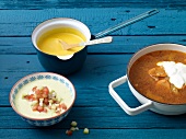 Three different types of vegetable soups in bowl and saucepan