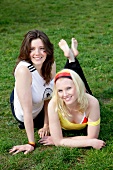 Portrait of two beautiful woman lying on grass, smiling