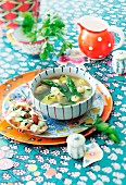 Kartoffel-Spargel-Suppe und Kräuterbrot auf bunt dekoriertem Tisch