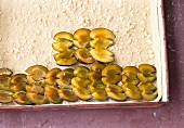 Pieces of plum arranged on dough for preparation of cheese cake, step 4, overhead view