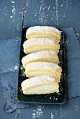 Slices of lemon cake roll with icing sugar on serving plate