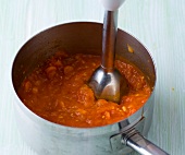 Tomatoes being crushed for preparing vegetarian Italian sauce, step 3