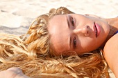 Frau liegt entspannt im Sand am Strand, close-up