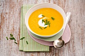 Orange ginger soup with carrot leaves in bowl