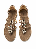 Pair of suede sandals with floral pattern on white background