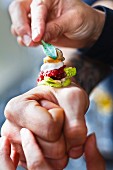 A canapé with oyster and tatar being served on the back of someone's hand at the restaurant De Librije (Netherlands)