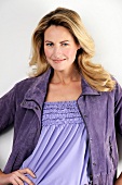 Portrait of pretty woman wearing purple jacket standing with hands on hip, smiling